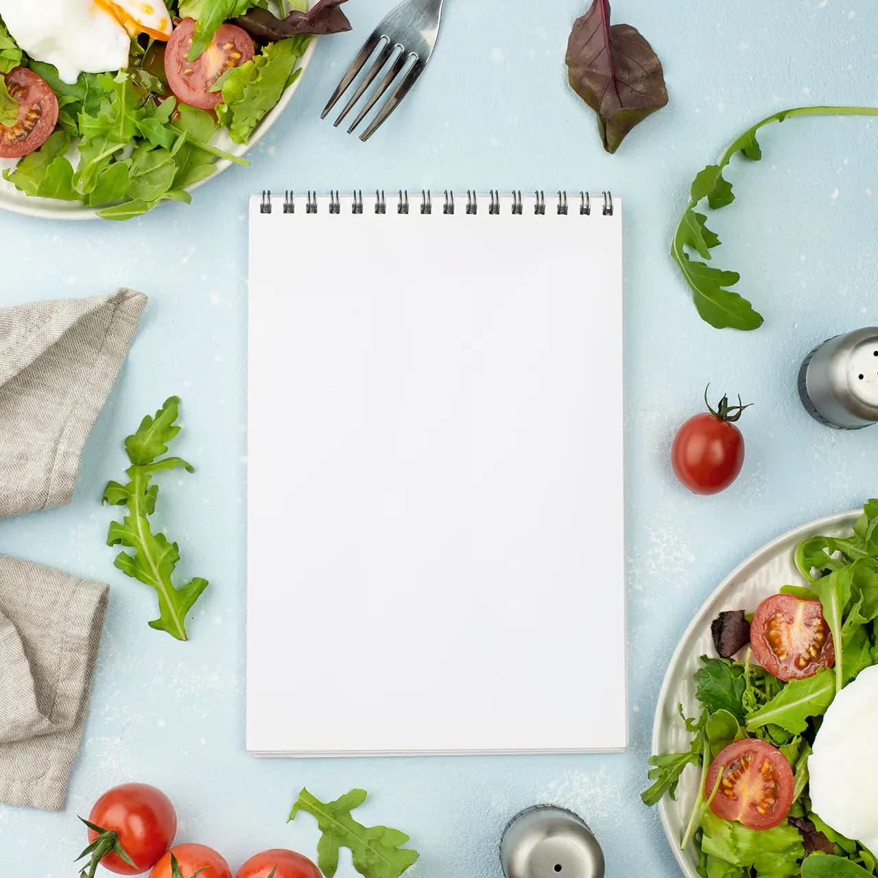 Blank notepad surrounded by fresh salad ingredients, used for planning the daycare’s food menu.